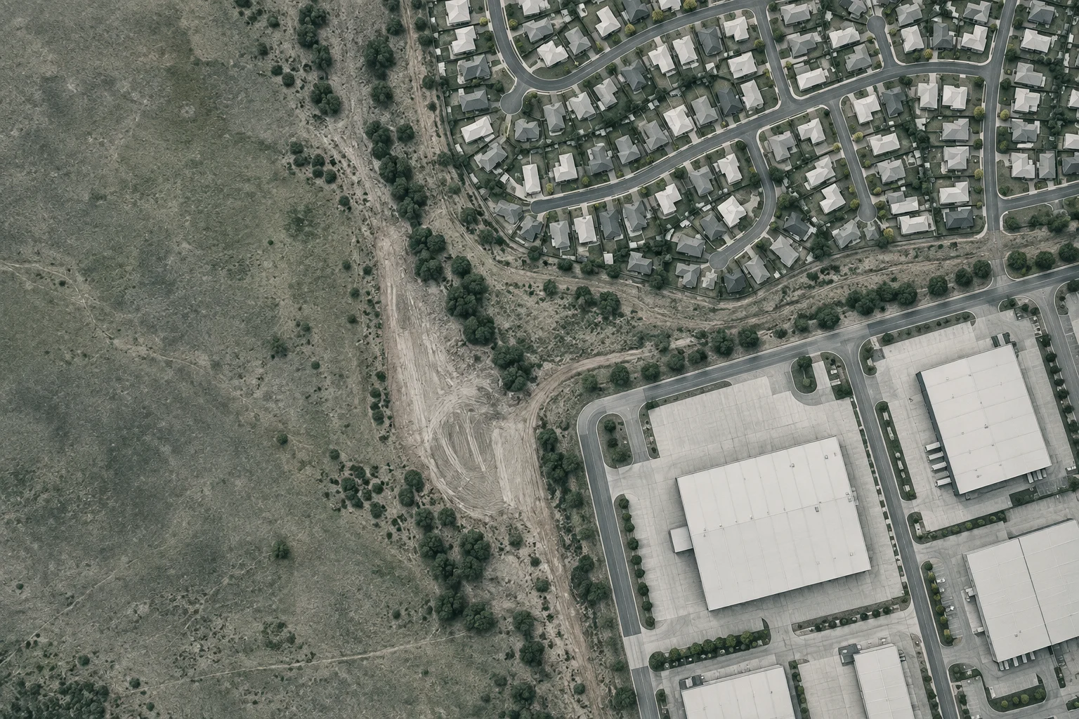 Illustrative aerial view of small residential lots and large commercial sites separated by undeveloped Australian land.